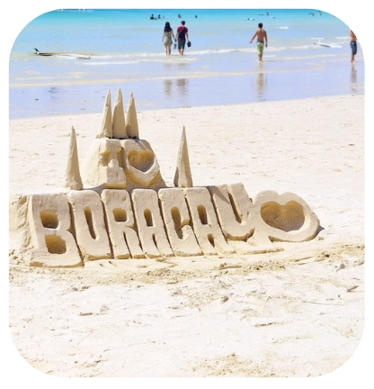 Sand sculpture that reads I love Boracay on White Beach with tourists and turquoise waters in the background