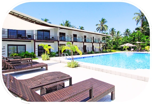 Beach resort in the Philippines with outdoor swimming pool, lounge chairs, and tropical palm trees